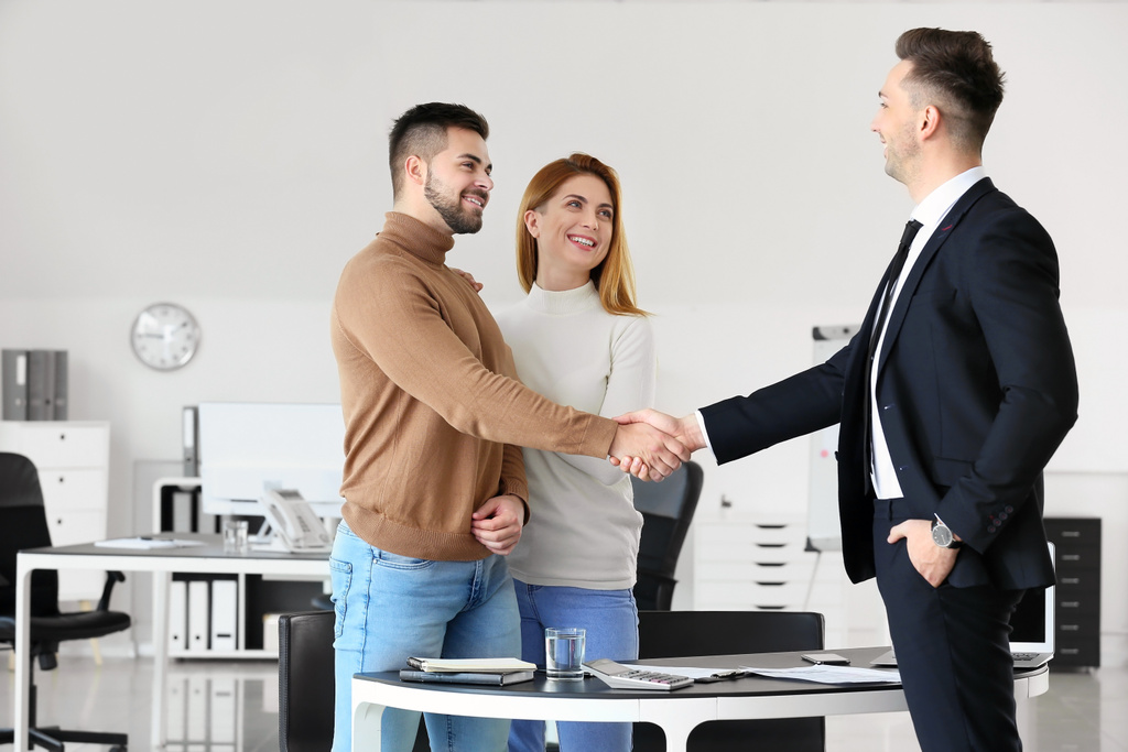 Bank manager and clients shaking hands in office